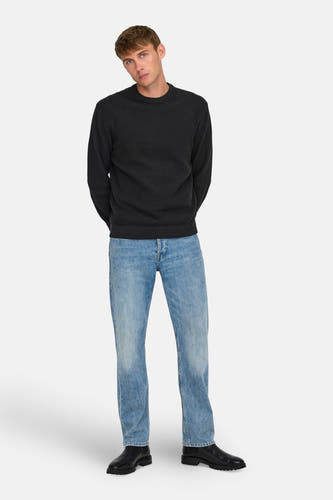 Pull noir avec col rond de ONLY & SONS®, porté avec des jeans bleus et des chaussures noires.