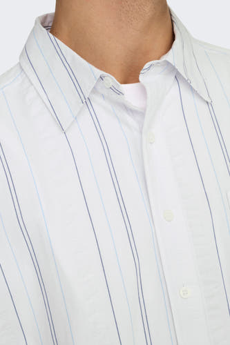 Wit overhemd met lange mouwen van ONLY & SONS®, gestreept patroon en knoopsluiting, gedragen over een wit shirt.
