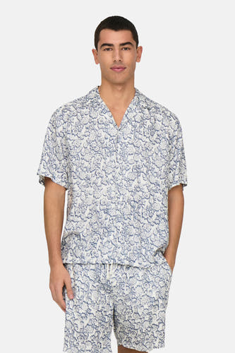 T-shirt à fleurs bleues à manches courtes de ONLY & SONS®, porté avec des shorts coordonnés et des baskets noires.