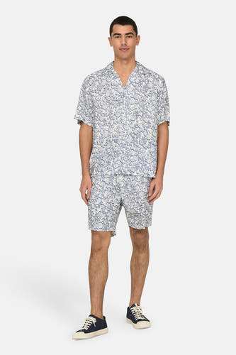 Blauw bloemen overhemd met korte mouwen van ONLY & SONS®, gedragen met bijpassende shorts en donkere sneakers.
