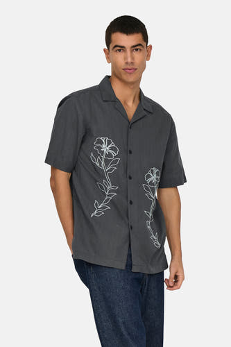 Chemise grise à manches courtes de ONLY & SONS, avec des motifs de fleurs brodés blancs et des jeans bleus marine.