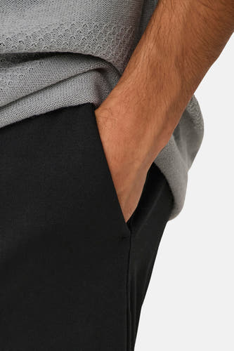 Zwarte broek van ONLY & SONS met hand in de zak, gedragen met grijze trui.

