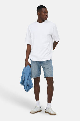Middenblauwe spijkerjeansshort van ONLY & SONS®, knie-lengte, gedragen door een man met wit T-shirt en witte sneakers.