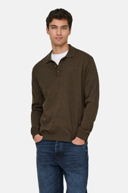 Bruine pull van ONLY & SONS, met lange mouwen, gedragen over een wit T-shirt en blauwe jeans, met de handen in de zakken.
