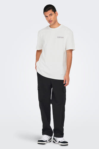 Wit T-shirt met korte mouwen van ONLY & SONS®, met een kleine opdruk, gecombineerd met een zwarte broek en sneakers.