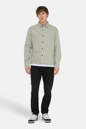 Groen overhemd met lange mouwen van ONLY & SONS®, met opgezette zakken en gedragen over een wit T-shirt en een zwarte jeans.

