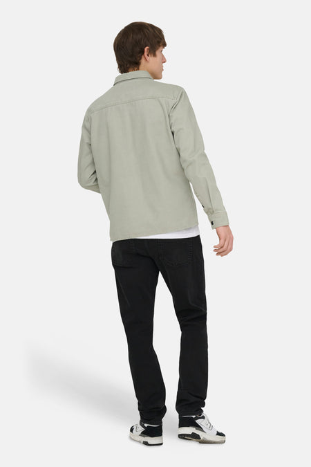 Groen hemd van ONLY & SONS, met lange mouwen, zichtbaar gedragen over een wit T-shirt en zwarte jeans.