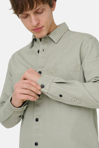Chemise verte ONLY & SONS®, à manches longues et poche poitrine, l'homme ferme les boutons des manches.