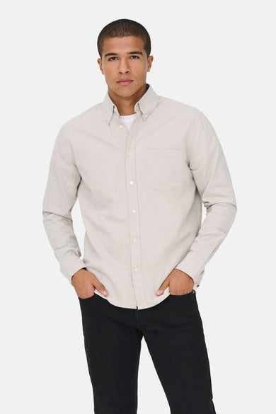 Chemise beige à longues manches de ONLY & SONS, avec une poche poitrine port portéeée un pantalon noir.