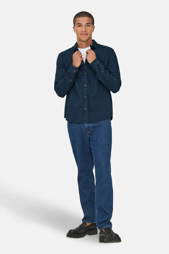 Blauw overhemd met lange mouwen van ONLY & SONS®, gedragen met een wit T-shirt en blauwe jeans, met zwarte schoenen.
