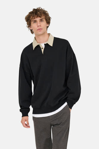 Pull-over noir d'ONLY & SONS, avec col beige et pantalon foncé.