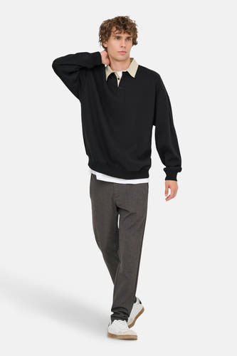 Pull-over noir d'ONLY & SONS, avec une encolure beige, porté avec un T-shirt blanc, un pantalon gris et des baskets blanches.