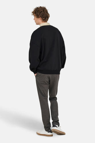 Pull-over noir d'ONLY & SONS, à longues manches, associé à un polo beige et un pantalon gris.