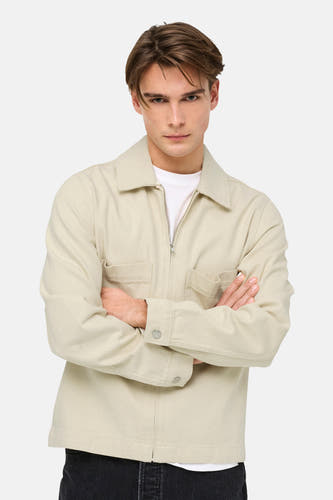 Ecru jeansjas van ONLY & SONS®, met lange mouwen en een ritssluiting, gedragen over een wit T-shirt.
