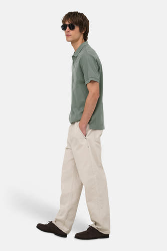 Groene polo van ONLY & SONS® in zijprofiel, met korte mouwen en klassieke kraag, gedragen met beige broek en donkere zonnebril.