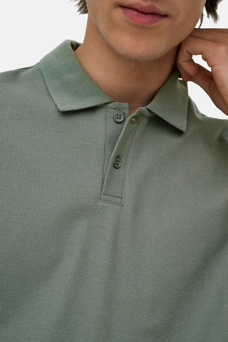 Groene polo met ribstructuur van ONLY & SONS®, close-up van kraag en knopen, model met hand bij nek
