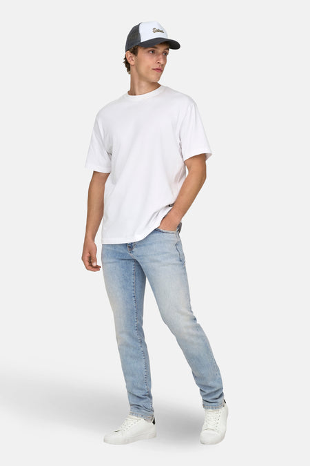 Slim fit jeans lichtblauwe denim van ONLY & SONS, met witte sneakers en een wit T-shirt.