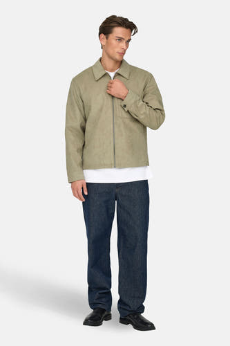 Manteau court beige de ONLY & SONS®, avec une fermeture éclair, un poche poitrine et porté avec un T-shirt blanc et des jeans bleu marine.