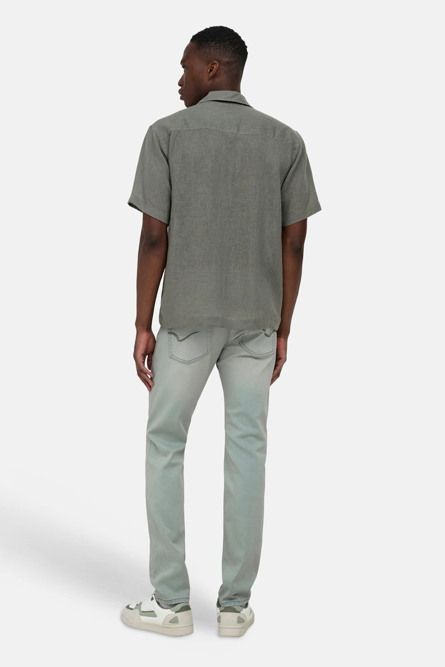 Kaki overhemd met korte mouwen van ONLY & SONS®, van textuurstof, gedragen door een man op de rug, gecombineerd met jeans en sneakers.