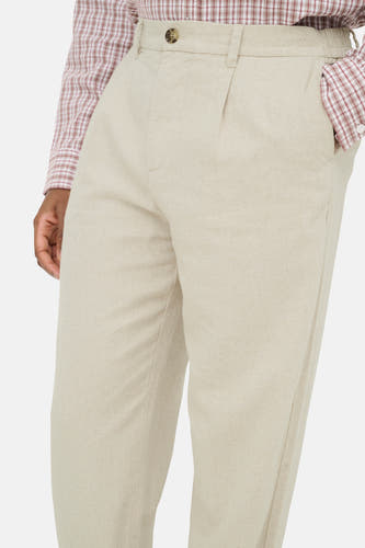 Beige broek van ONLY & SONS met knoopsluiting, plissé voorkant en elastische tailleband, gedragen met geruit overhemd.