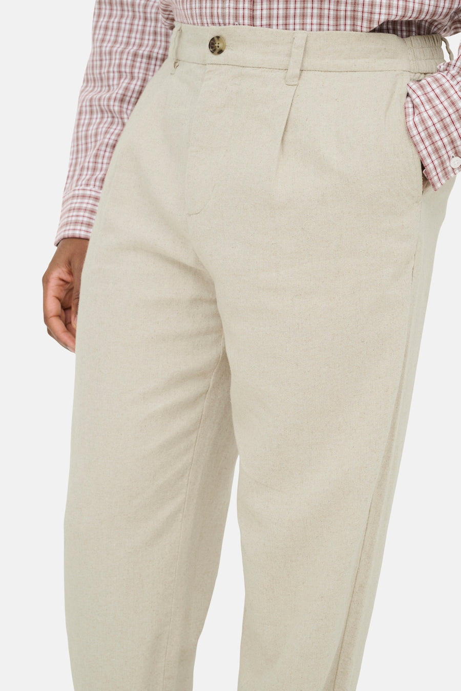 Beige broek van ONLY & SONS met knoopsluiting, plissé voorkant en elastische tailleband, gedragen met geruit overhemd.