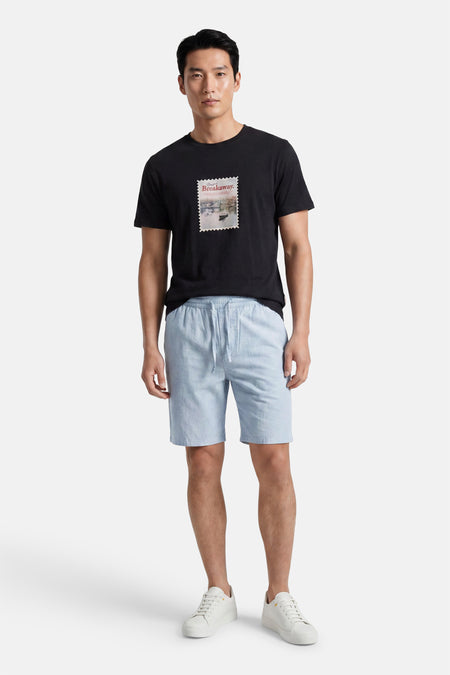 Lichtblauwe short van ONLY & SONS® met trekkoord, gedragen door een man met een zwart T-shirt en witte sneakers.