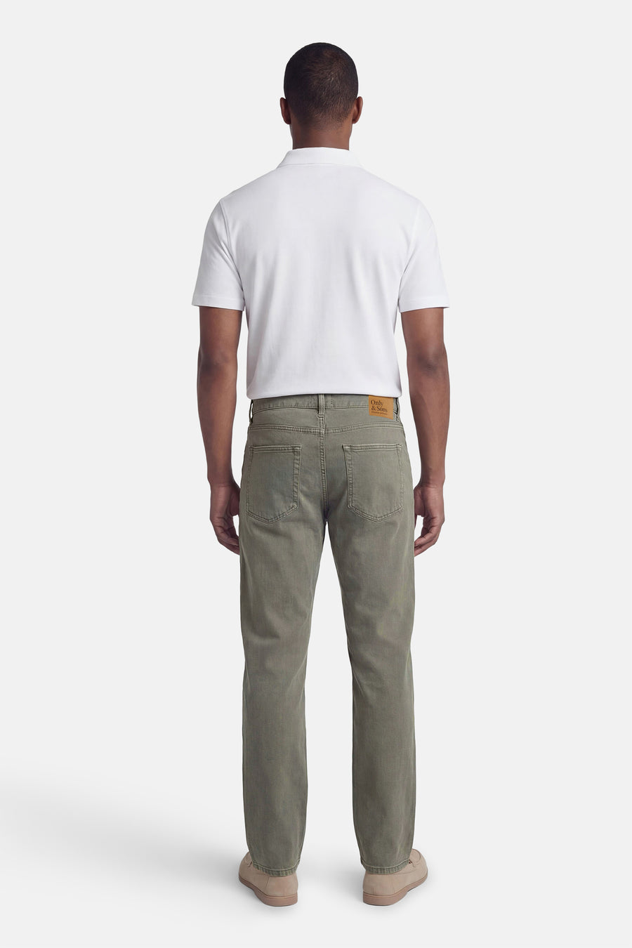 Khaki heren jeans van ONLY & SONS®, met achterzakken, gecombineerd met een wit poloshirt en beige schoenen.
