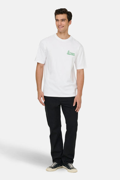 Wit T-shirt met korte mouwen van ONLY & SONS®, met een groene tekstprint en gedragen met een zwarte broek en zwarte sneakers.