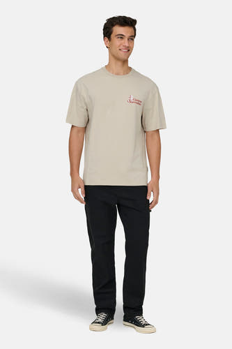 Ecru T-shirt met korte mouwen van ONLY & SONS®, met rode print op de borst, gecombineerd met zwarte broek en schoenen.
