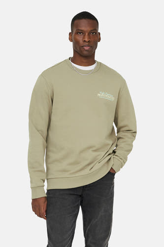 Beige sweater met ronde hals van ONLY & SONS, met lange mouwen en een gedrukte tekst vooraan, gecombineerd met een zilveren ketting.
