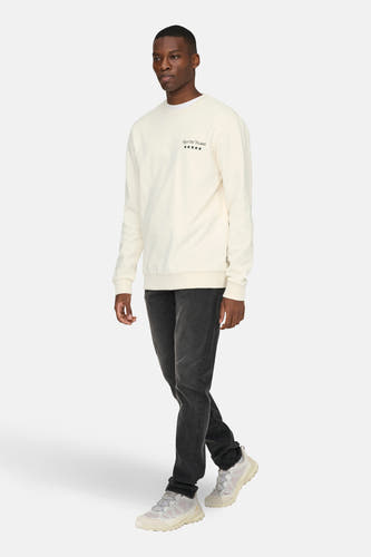 Witte sweater met ronde hals van ONLY & SONS®, met klein logo Rue de Flores op de borst, gecombineerd met een donkere jeans en lichte sneakers.
