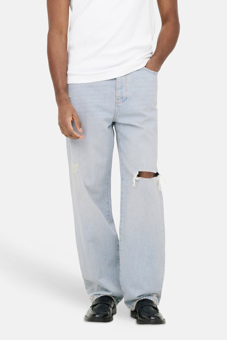 Jean large bleu clair ONLY & SONS avec déchirure au genou, porté par un homme.