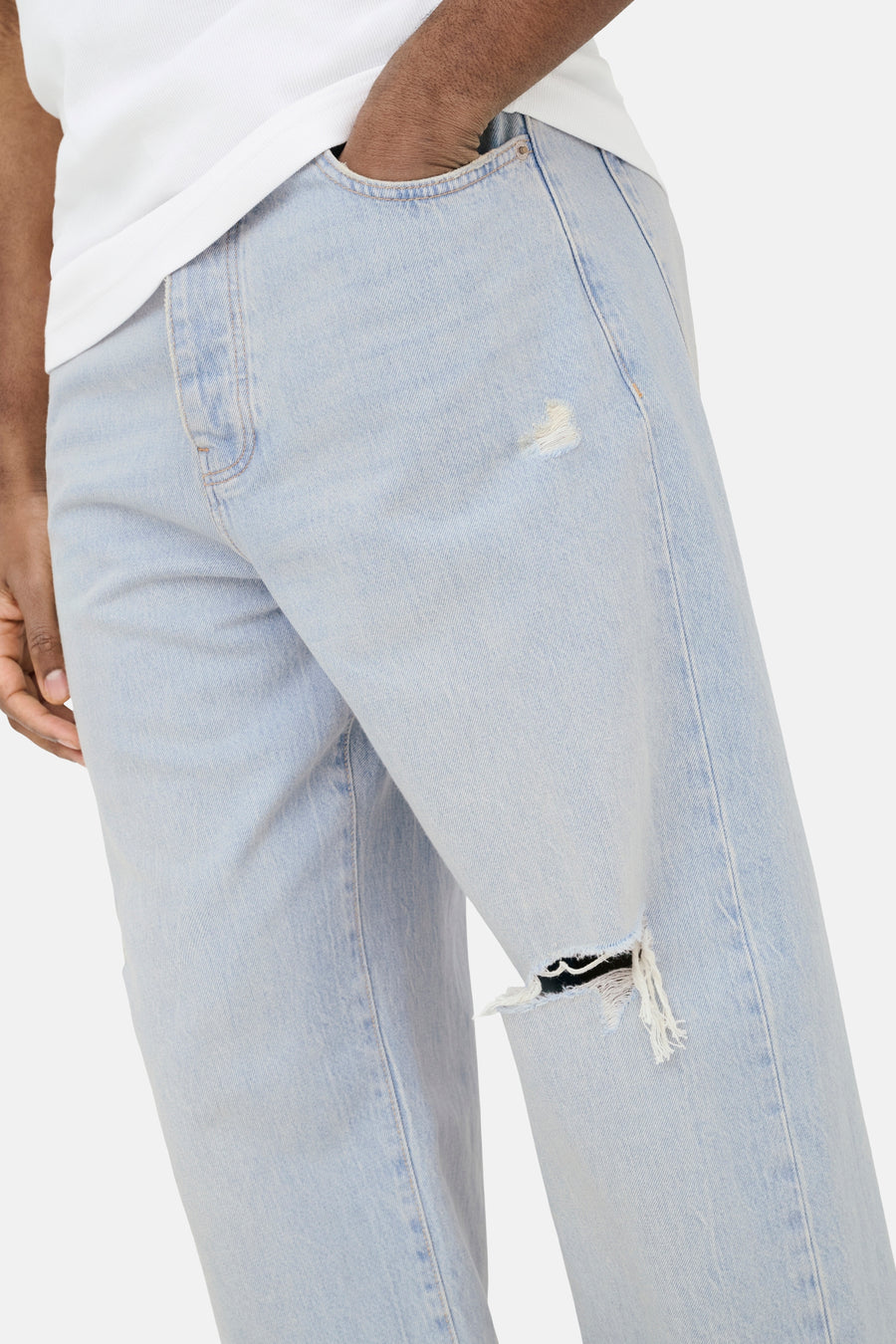 Lichtblauwe wijde denim jeans van ONLY & SONS® met scheuren, een hand in de zak en een wit T-shirt.