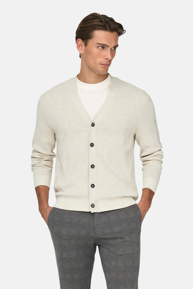 Ecru gilet van ONLY & SONS®, gedragen over een wit t-shirt, met grijze pantalon en gouden armband.
