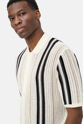 Ecru pull van ONLY & SONS® met polokraag, open gebreide textuur, zwarte en grijze verticale strepen en korte mouwen, gedragen door een man.