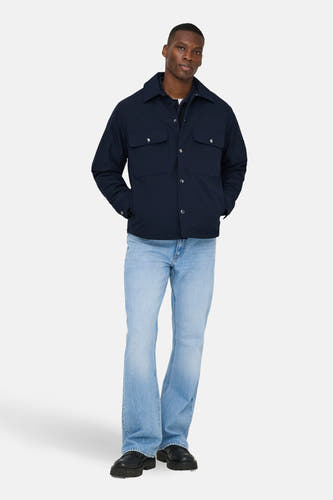 Manteau bleu court d'ONLY & SONS porté sur une chemise, avec des jeans bleus clairs et des chaussures noires.