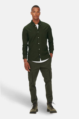 Chemise verte à longues manches de ONLY & SONS, portée sur un T-shirt blanc et des pantalons cargo verts avec des bottes brunes.