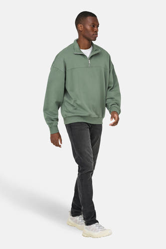 Pull-over vert de ONLY & SONS, avec une fermeture éclair courte et porté avec des jeans foncés et des baskets blanches.