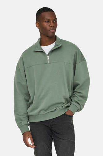Sweater vert de ONLY & SONS, avec une fermeture à glissière courte, porté sur un T-shirt blanc et un jean noir.