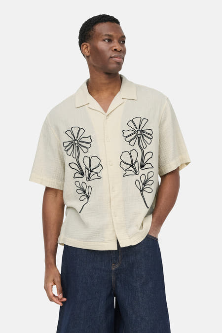 Ecru overhemd met korte mouwen van ONLY & SONS® met zwarte bloemenprints op gestructureerde stof, gedragen door een man.