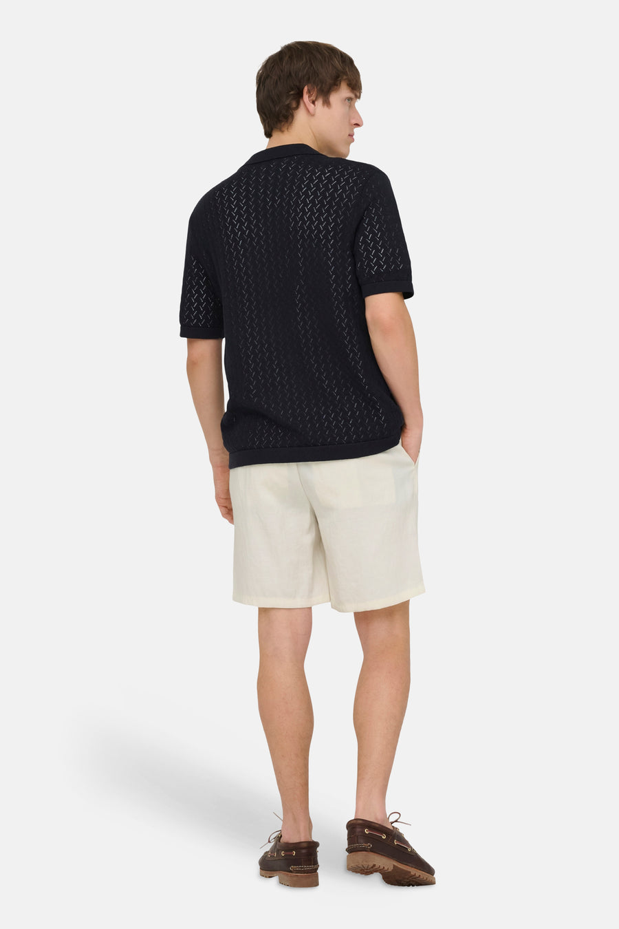 Ecru short van ONLY & SONS, gecombineerd met een zwart poloshirt met patroon en bruine bootschoenen.