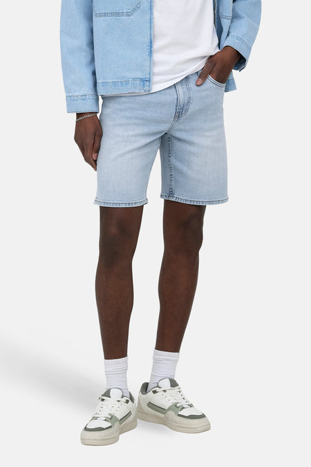 Jeansshort van lichtblauw denim van ONLY & SONS, met een relaxte pasvorm en gedragen met een wit T-shirt, spijkerjack en sneakers.