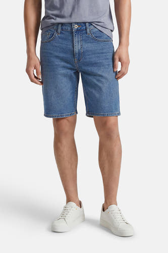 Mid-blauwe denim short van ONLY & SONS® met klassieke zakken en knoopsluiting, gedragen door een man.