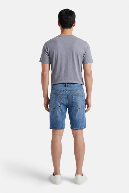 Mid-blauwe denim jeansshort van ONLY & SONS®, rugzicht, gedragen met een grijs T-shirt en witte sneakers.