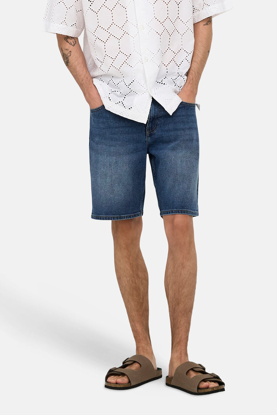 Short en jean bleu moyen de ONLY & SONS®, porté par un homme avec une chemise blanche et des sandales marron.