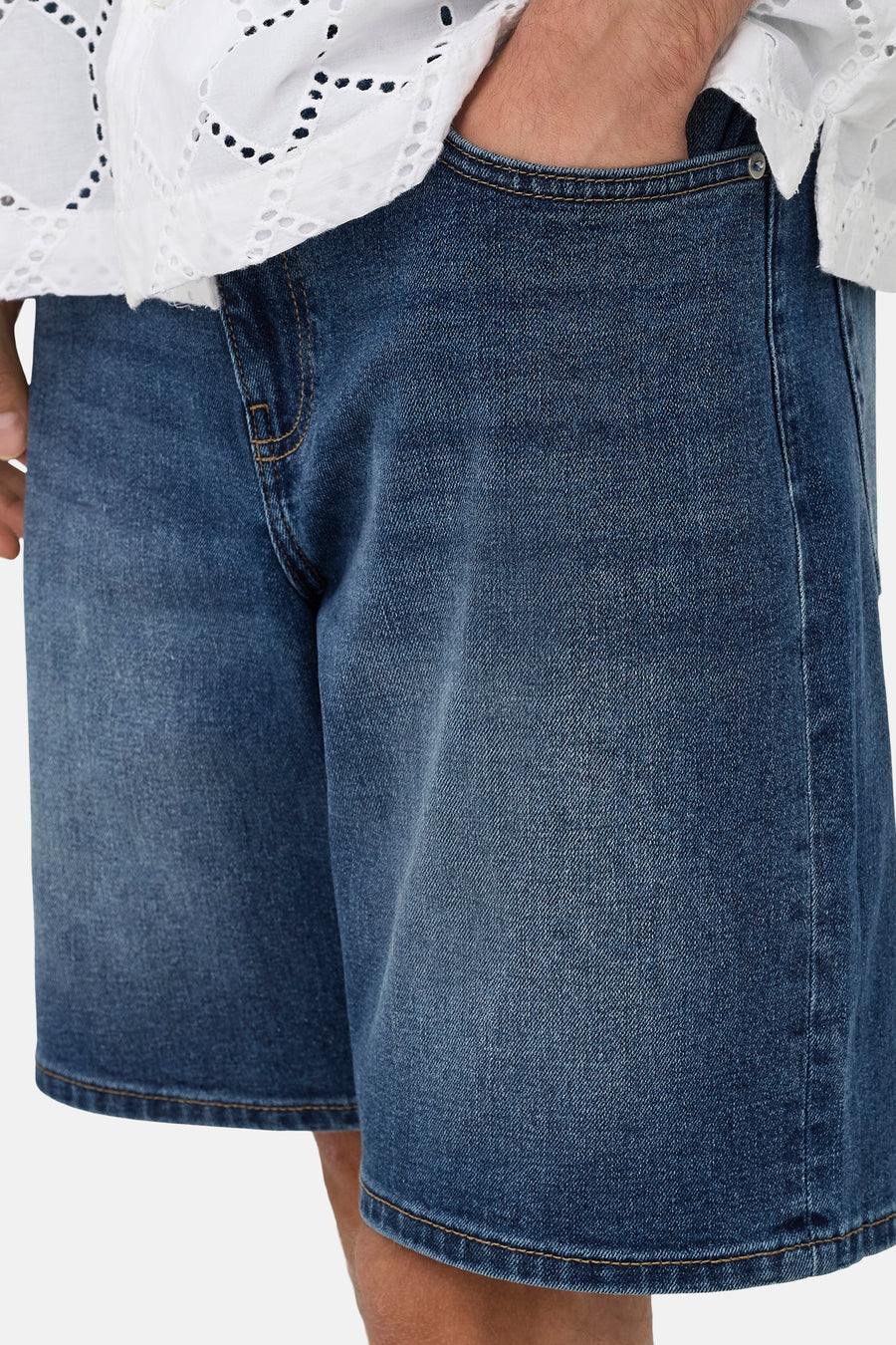 Short en jean de couleur bleu moyen ONLY & SONS® avec coutures marron clair et une chemise blanche brodée.