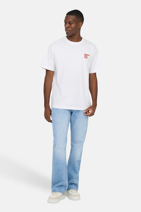 T-shirt blanc à manches courtes ONLY & SONS®, avec texte rouge, combiné avec un jean bleu clair.
