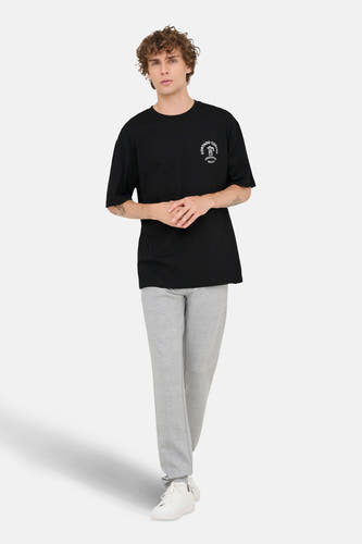 T-shirt noir à manches courtes de ONLY & SONS®, porté avec un pantalon de jogging gris et des baskets blanches.
