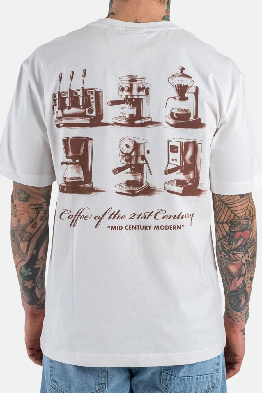Wit T-shirt met korte mouwen van ONLY & SONS®, met bruine koffiezetapparaat-illustraties en tekst op de rug, gedragen met een blauwe jeans.
