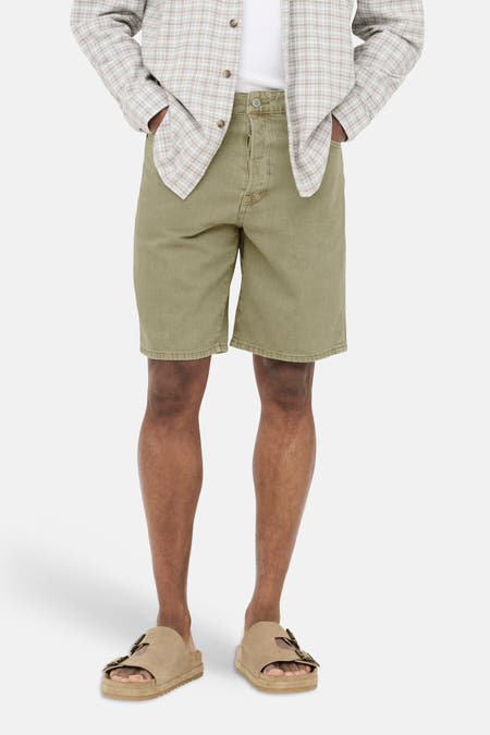 Short en jean beige de ONLY & SONS, porté par un homme avec une chemise à carreaux ouverte et des sandales.